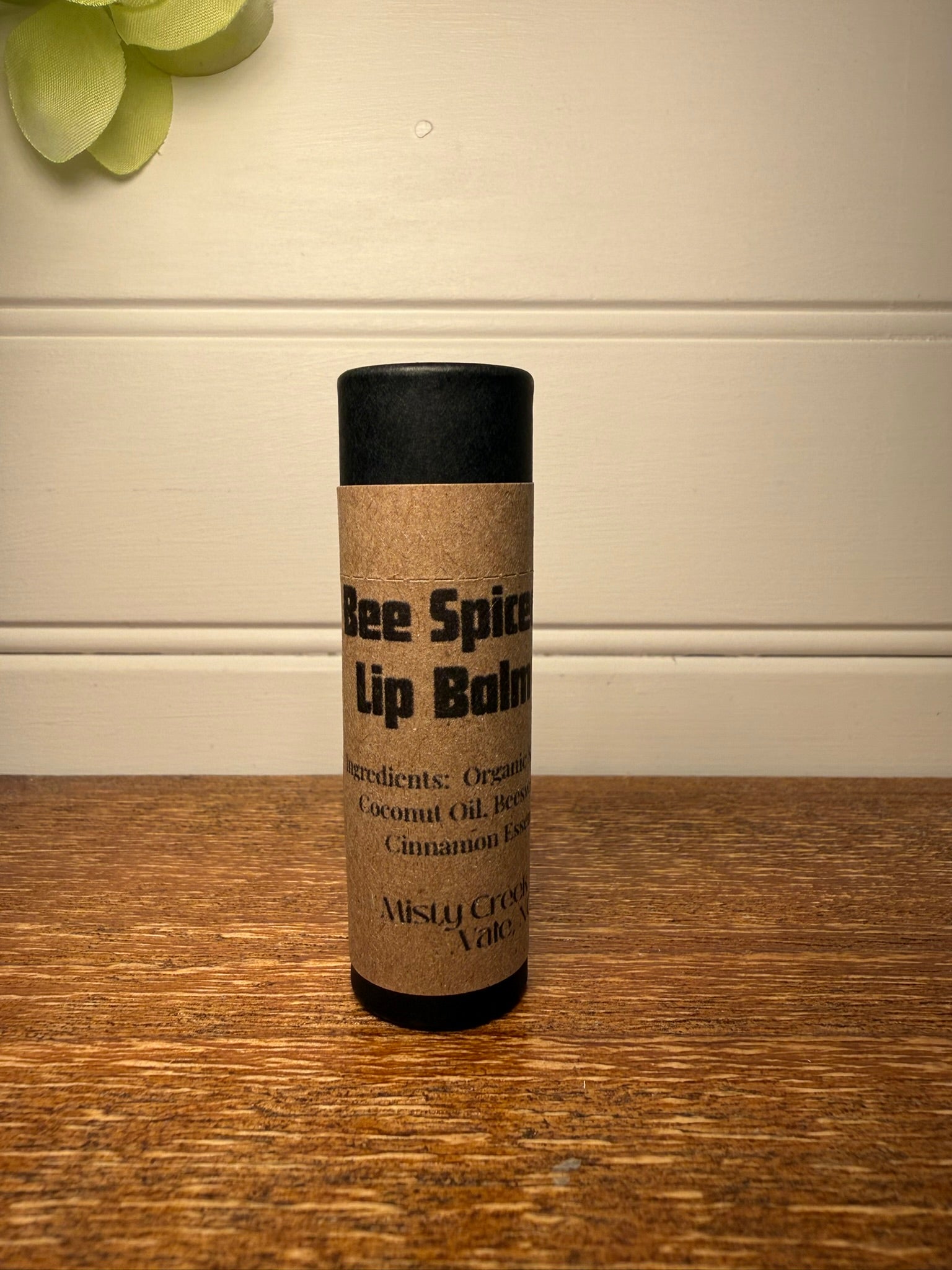 Lip balm container with label on a wooden surface