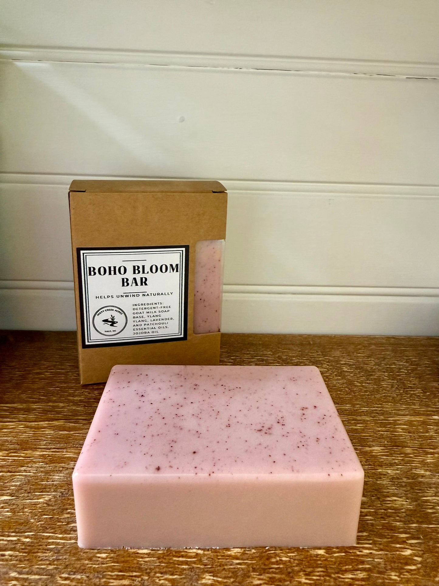 Pink soap bar with 'Boho Bloom Bar' packaging on a wooden surface.