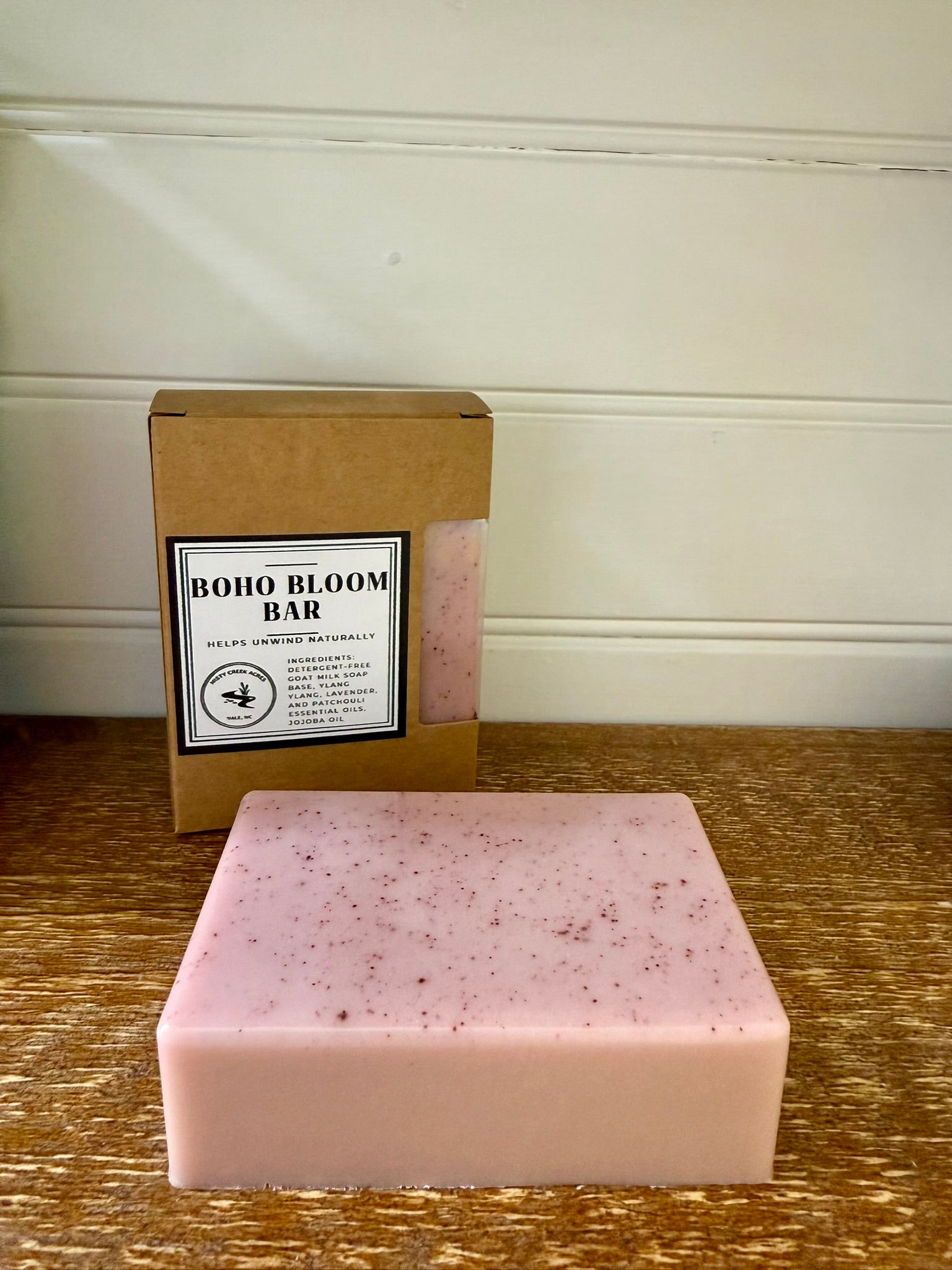 Pink soap bar with 'Boho Bloom Bar' packaging on a wooden surface.