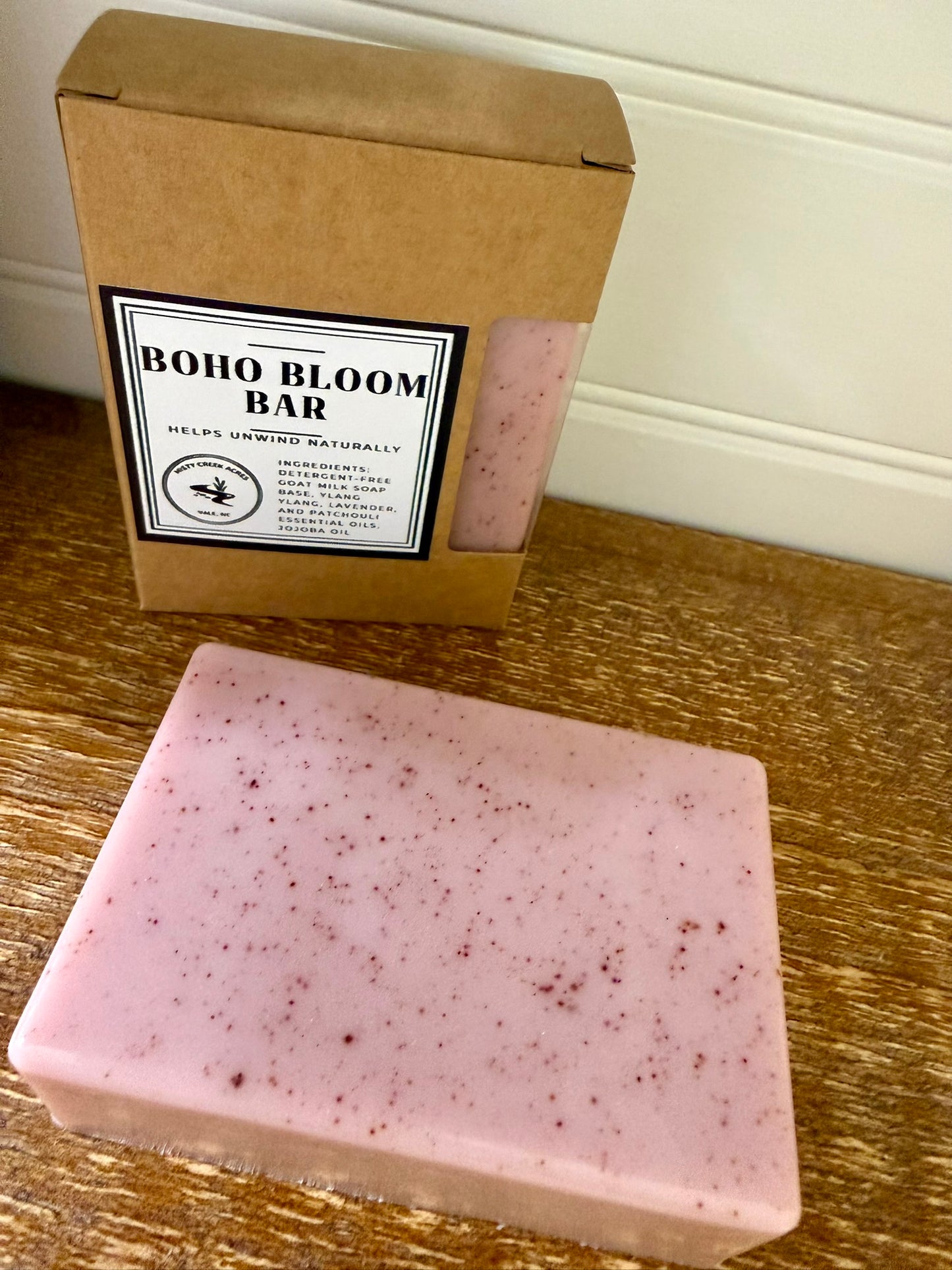 Pink soap bar with 'Boho Bloom Bar' packaging on a wooden surface