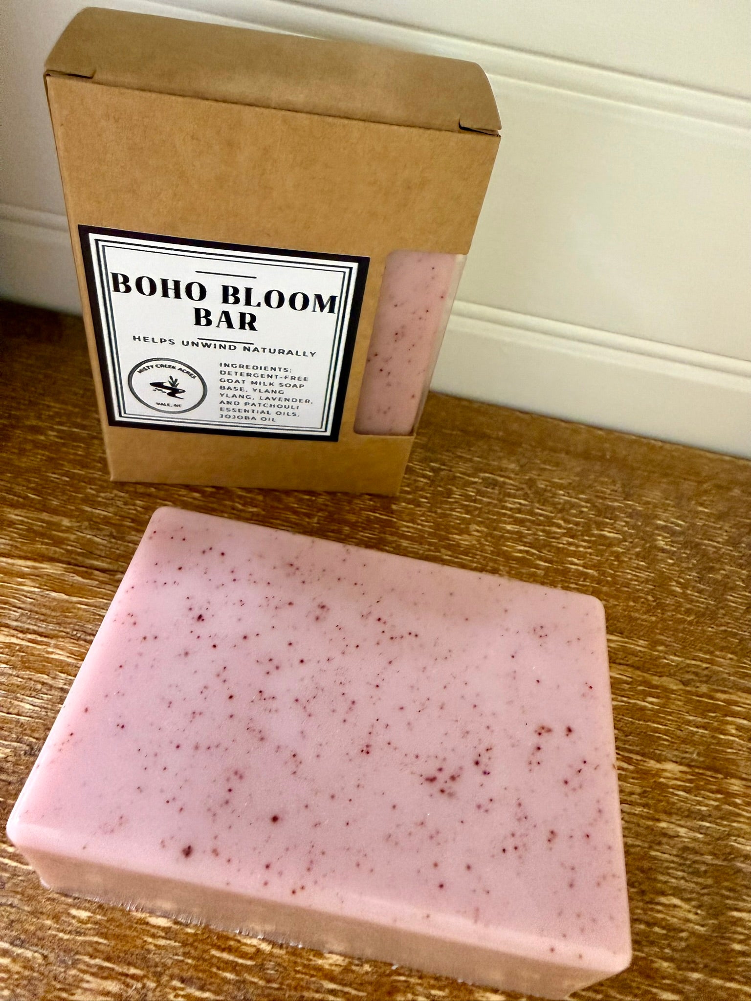 Pink soap bar with 'Boho Bloom Bar' packaging on a wooden surface