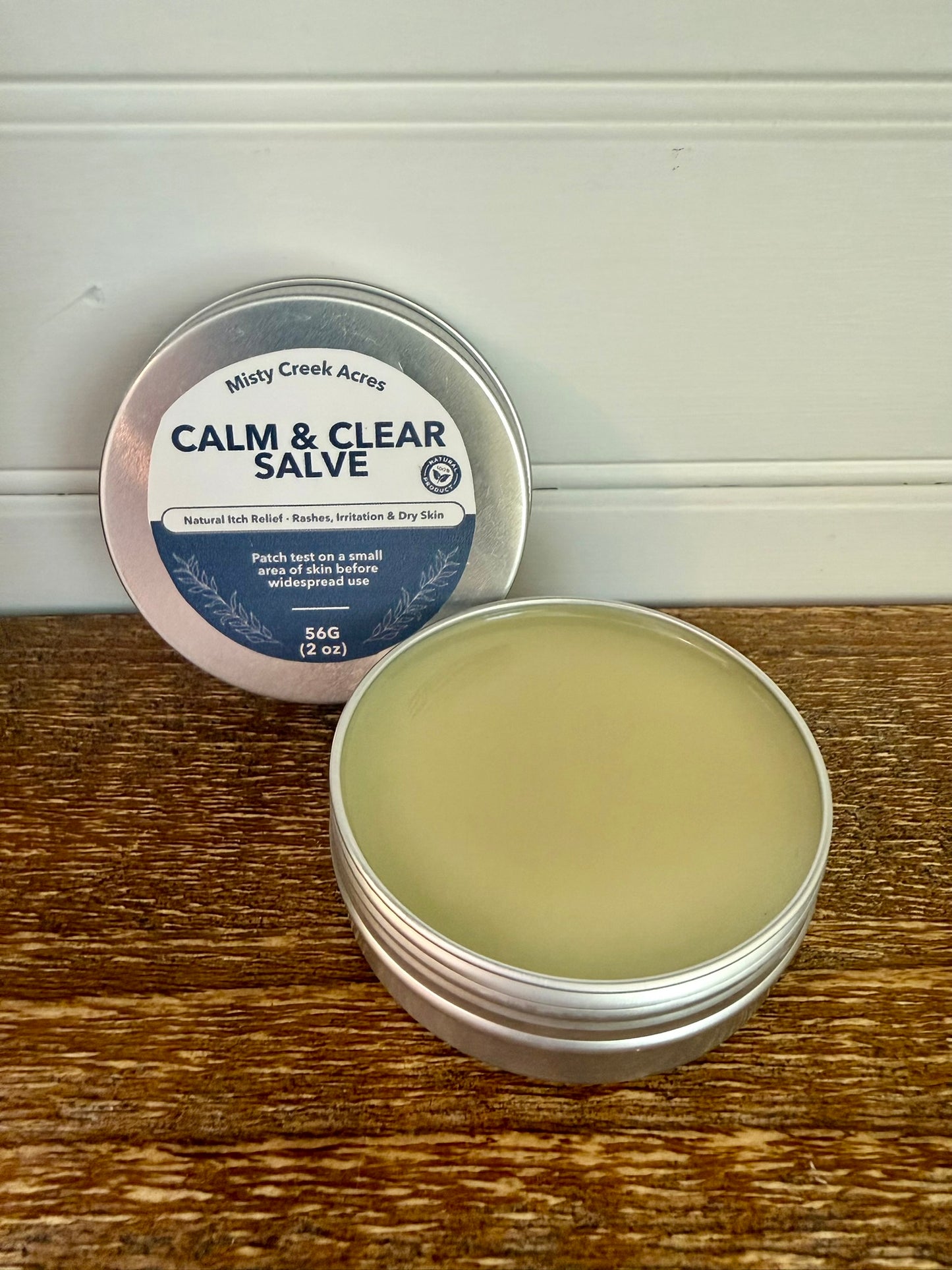 Calm & Clear Salve container on a wooden surface with a white background