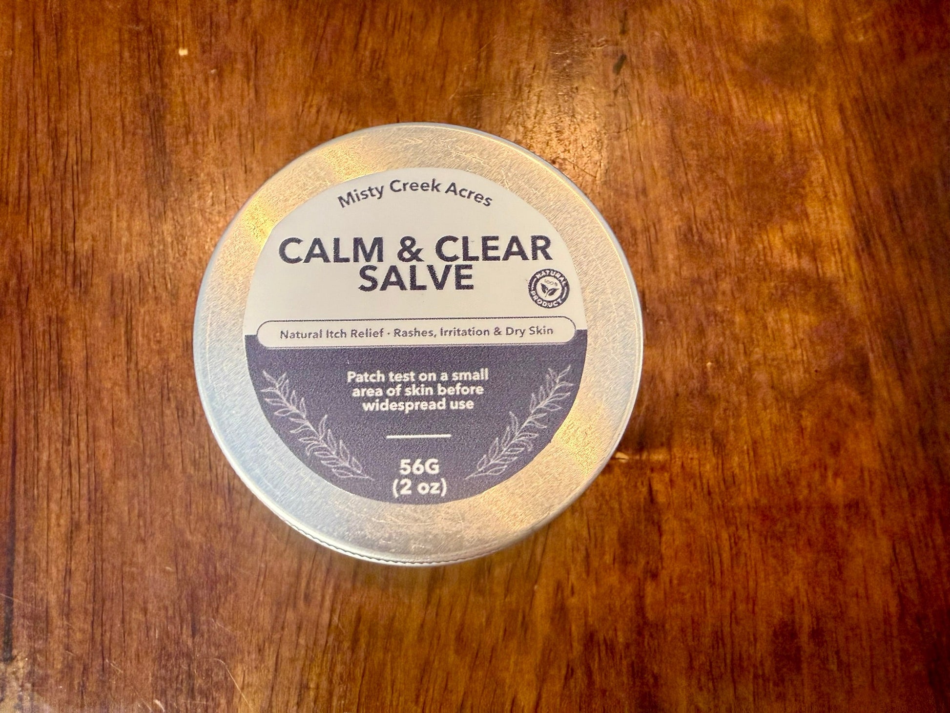 Container of Calm & Clear Salve on a wooden surface