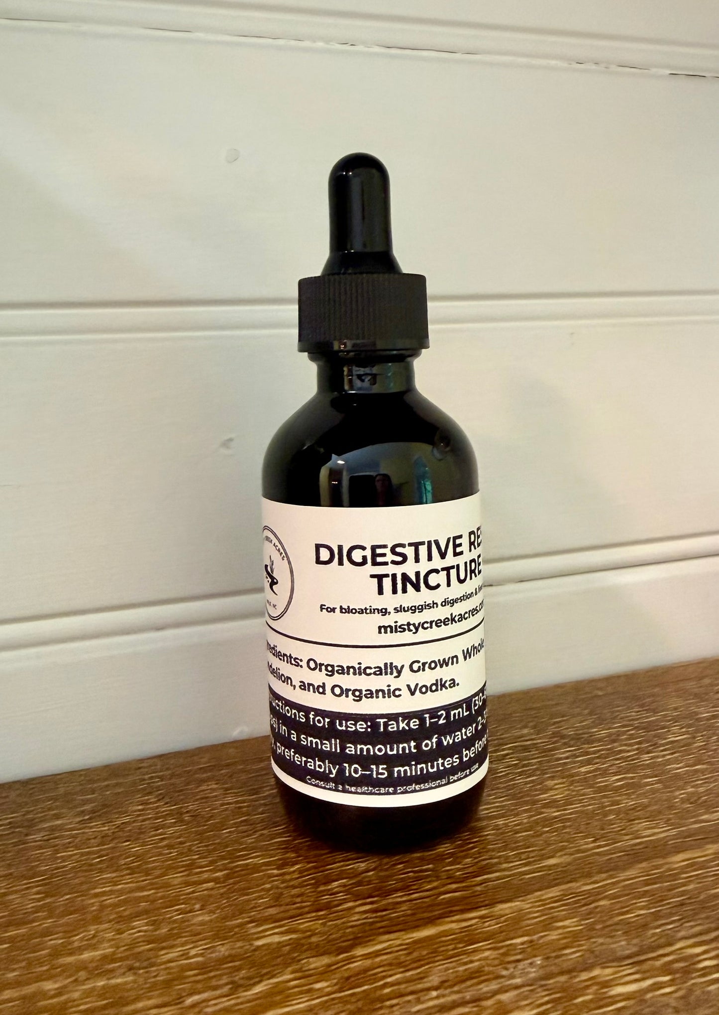 Bottle of digestive tincture on a wooden surface with a white wall background