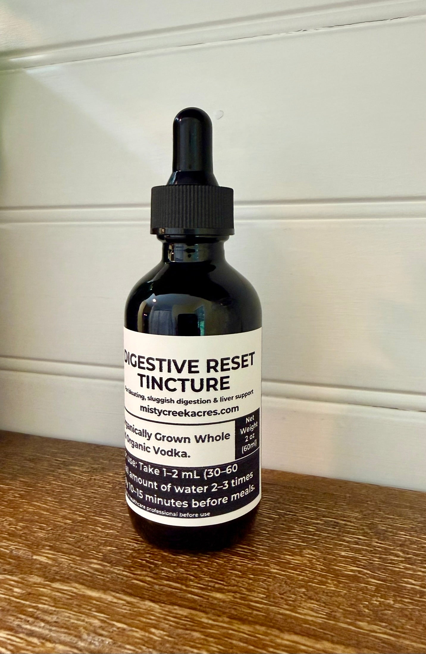 Bottle of Digestive Reset Tincture on a wooden surface with a white background