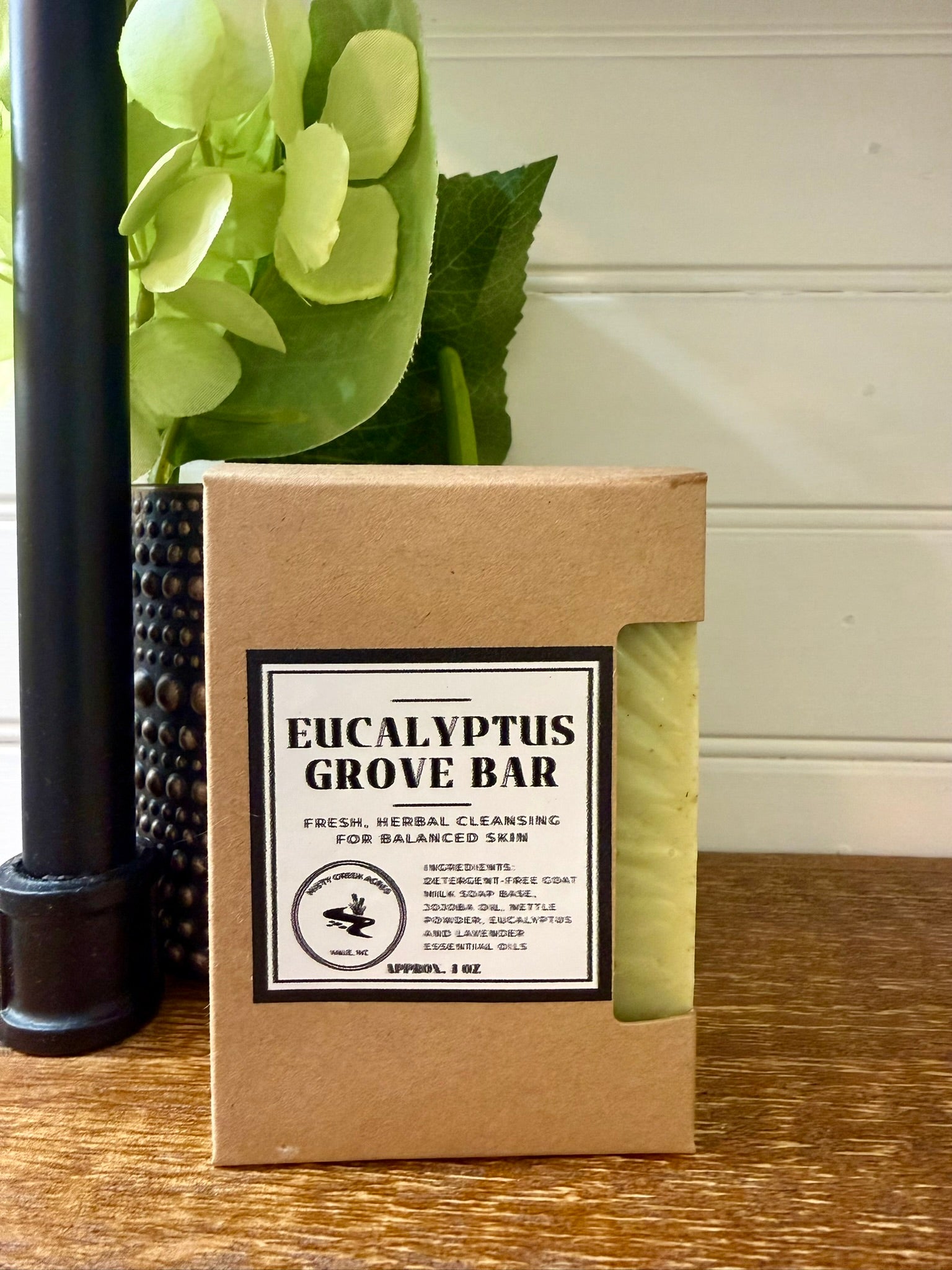 Eucalyptus Grove Bar packaging on a wooden surface with a plant in the background