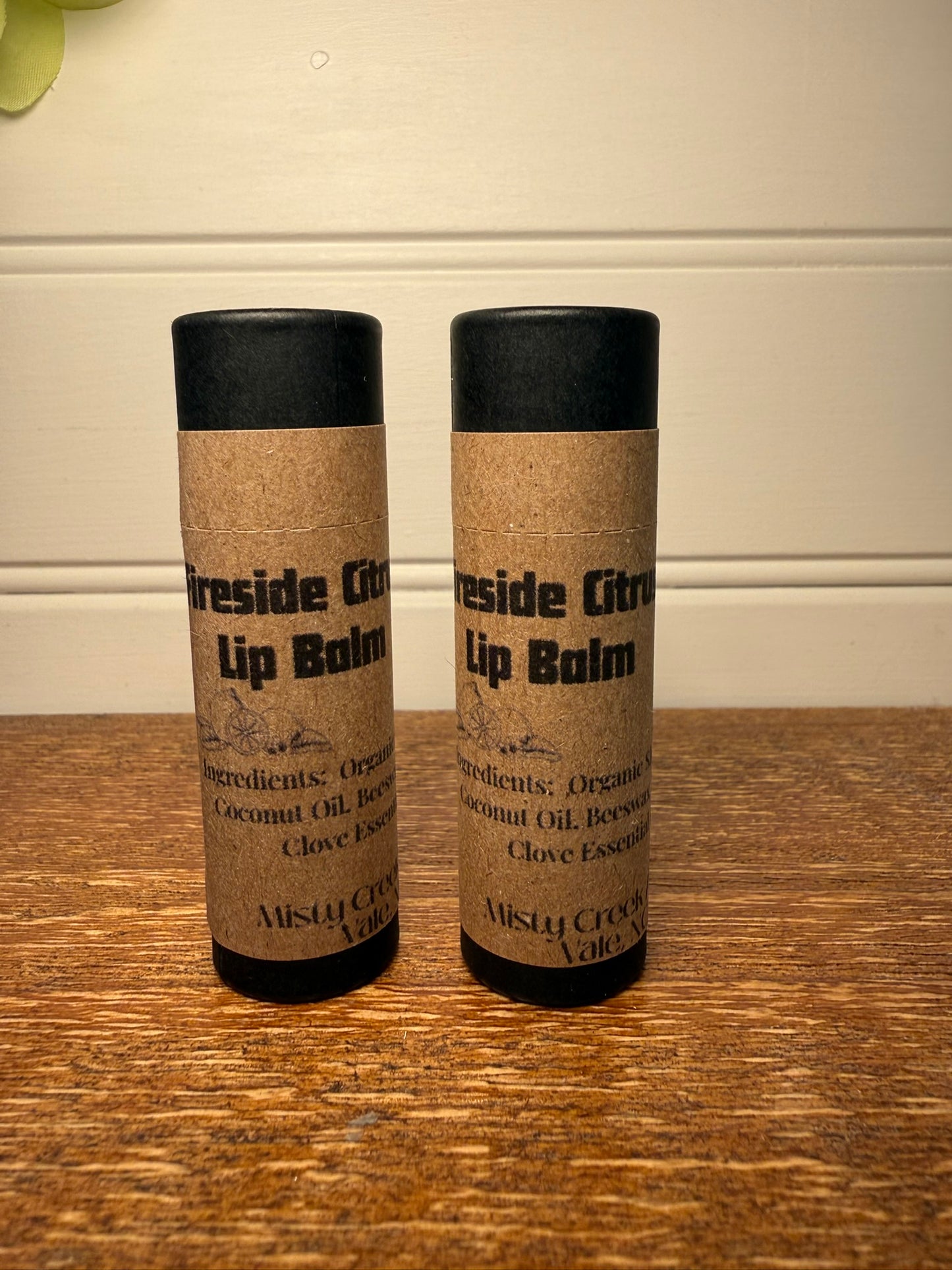 Two lip balms with cork-like packaging on a wooden surface.
