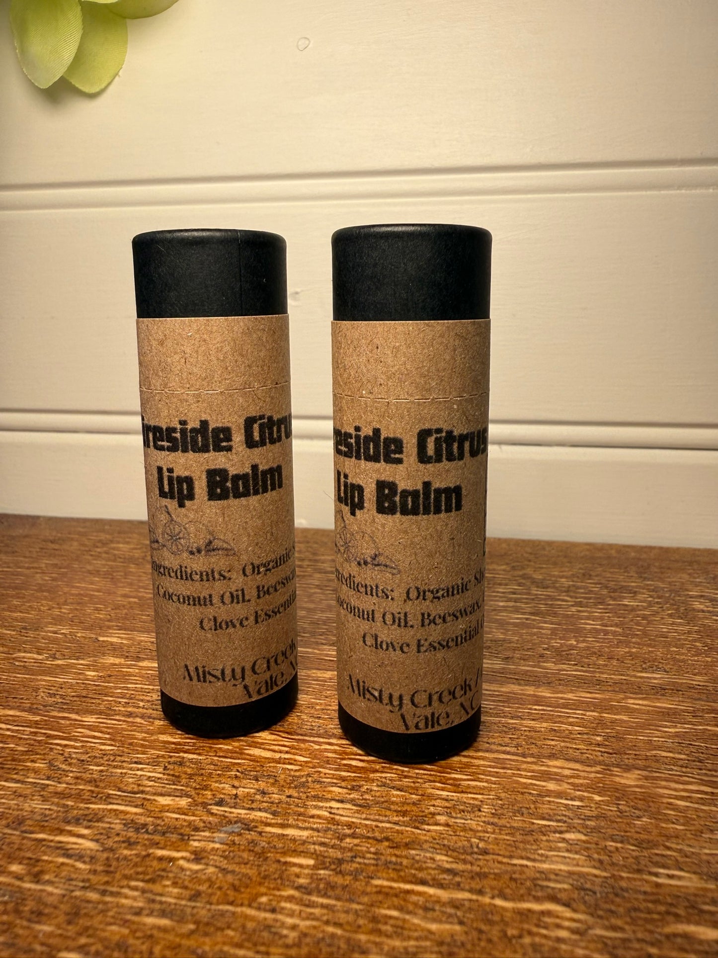 Two lip balms labeled 'Inside Citrus' on a wooden surface with a neutral background.
