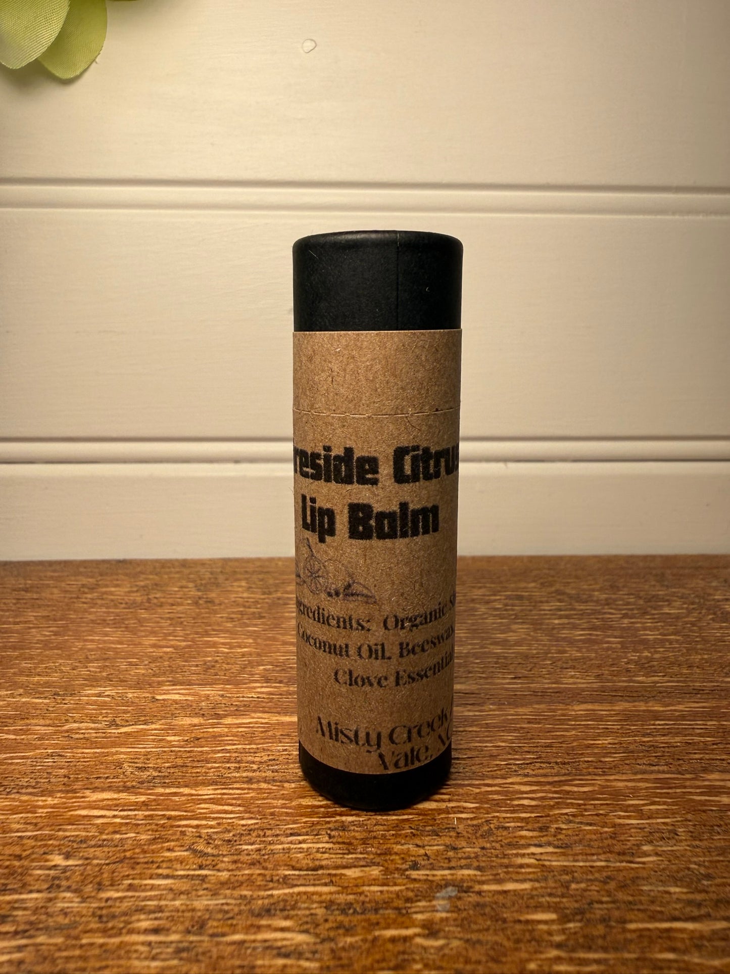 Lip balm container with cork sleeve on a wooden surface