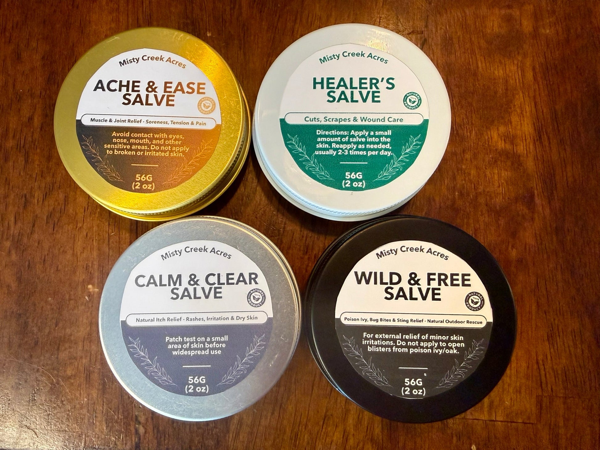 Four containers of different salves on a wooden surface