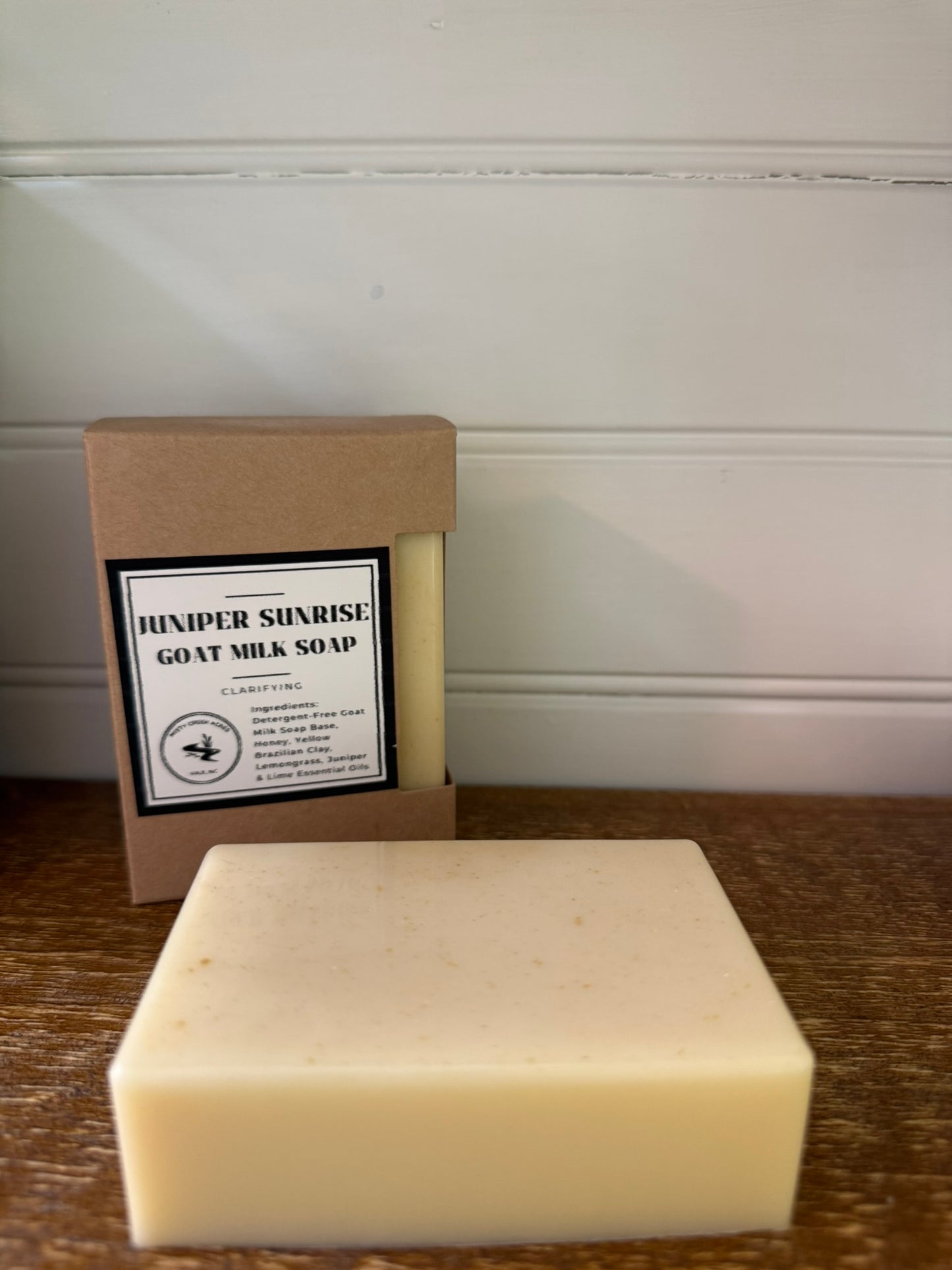 Bar of soap and its packaging with 'Hexxer Sunrise Goat Milk Soap' label on a wooden surface.