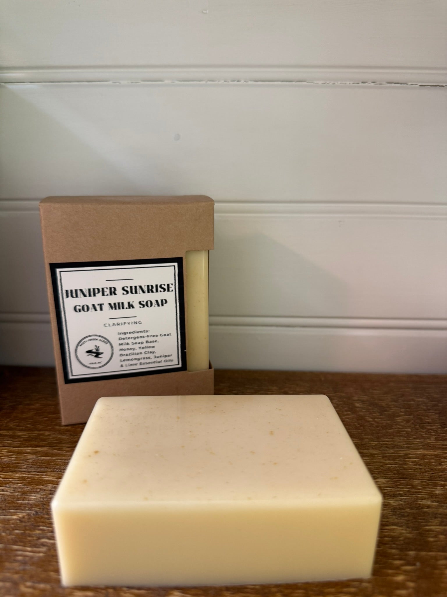 Bar of soap and its packaging with 'Hexxer Sunrise Goat Milk Soap' label on a wooden surface.