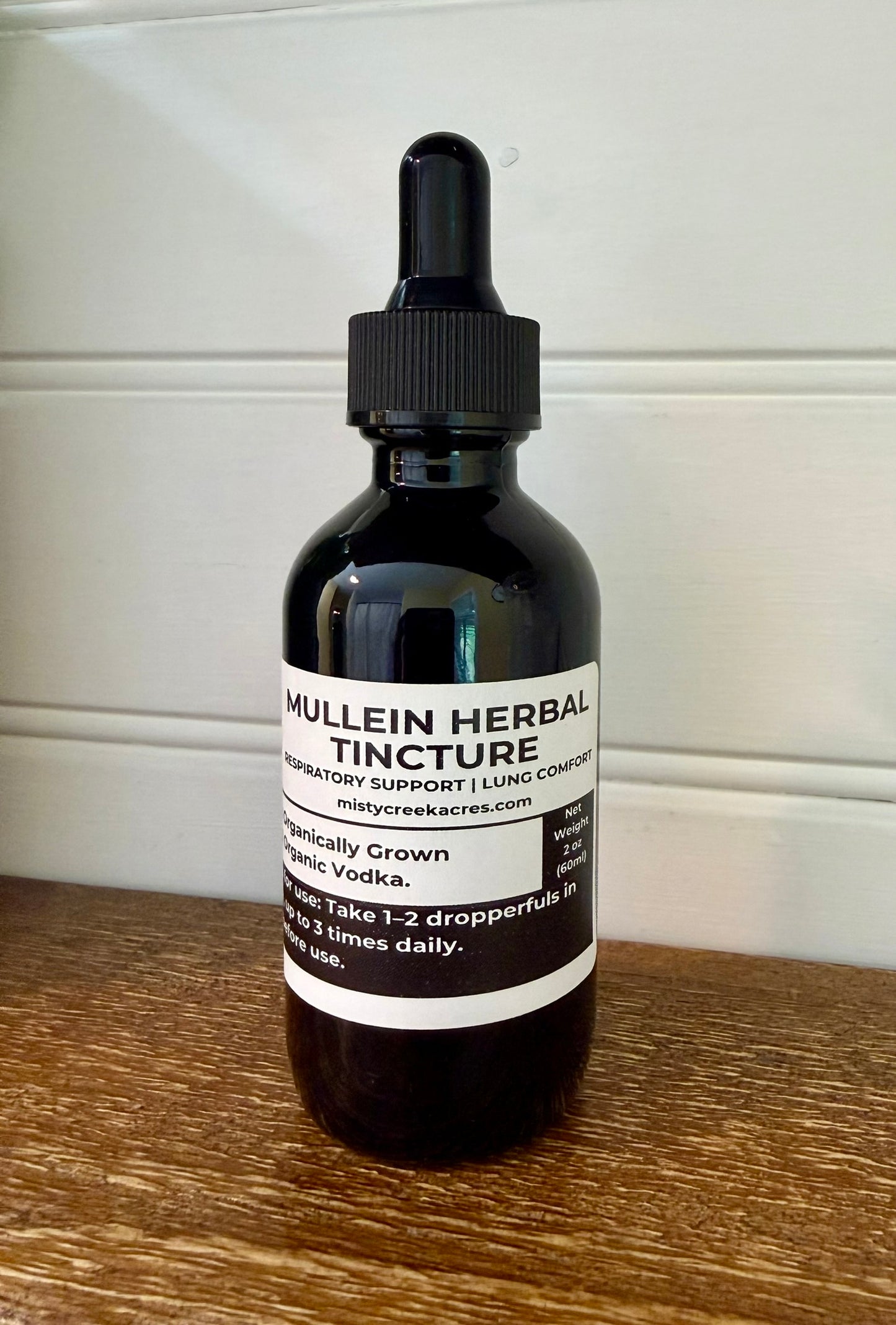 Bottle of mullein herbal tincture on a wooden surface with a white background