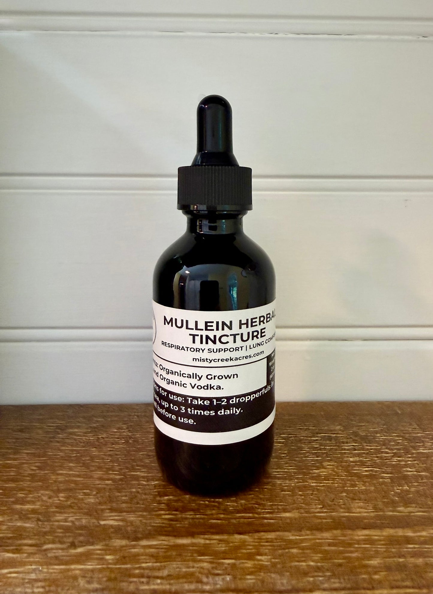 Bottle of Mullein Herbal Tincture on a wooden surface with a white wall background