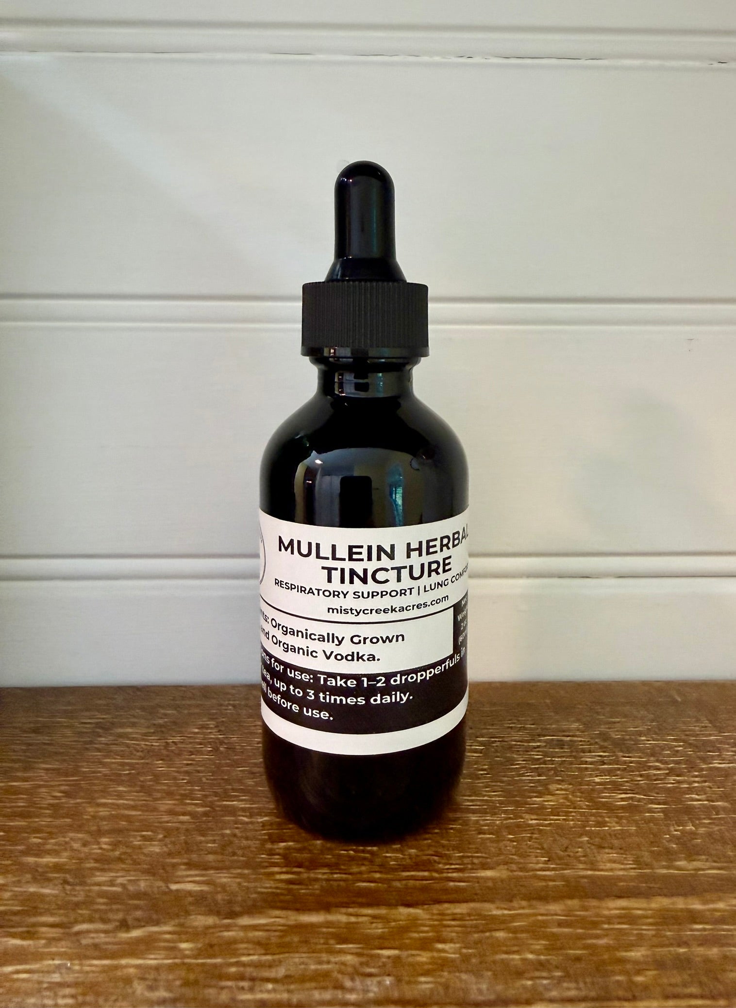 Bottle of Mullein Herbal Tincture on a wooden surface with a white wall background