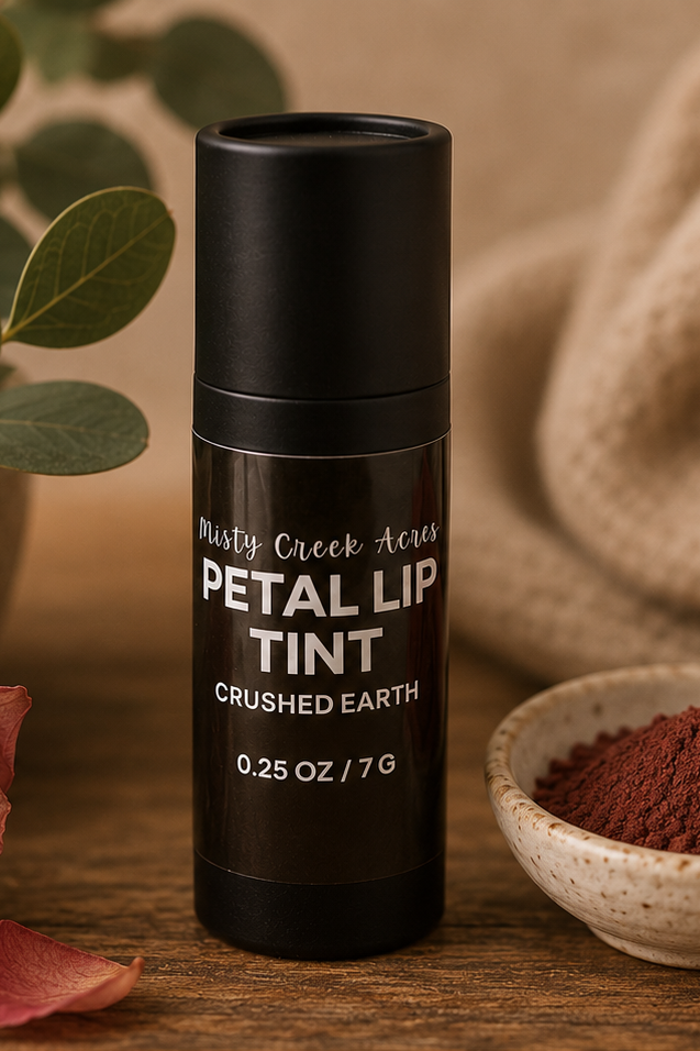 Black lip tint container with rose, bowl of powder, and plant on wooden surface