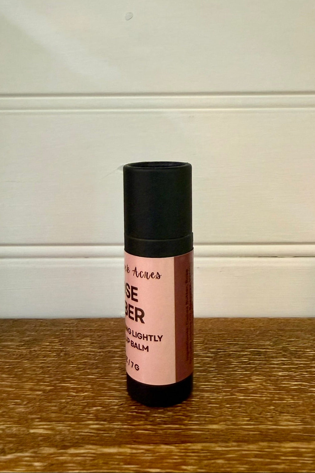 Small roller bottle with pink label on a wooden surface