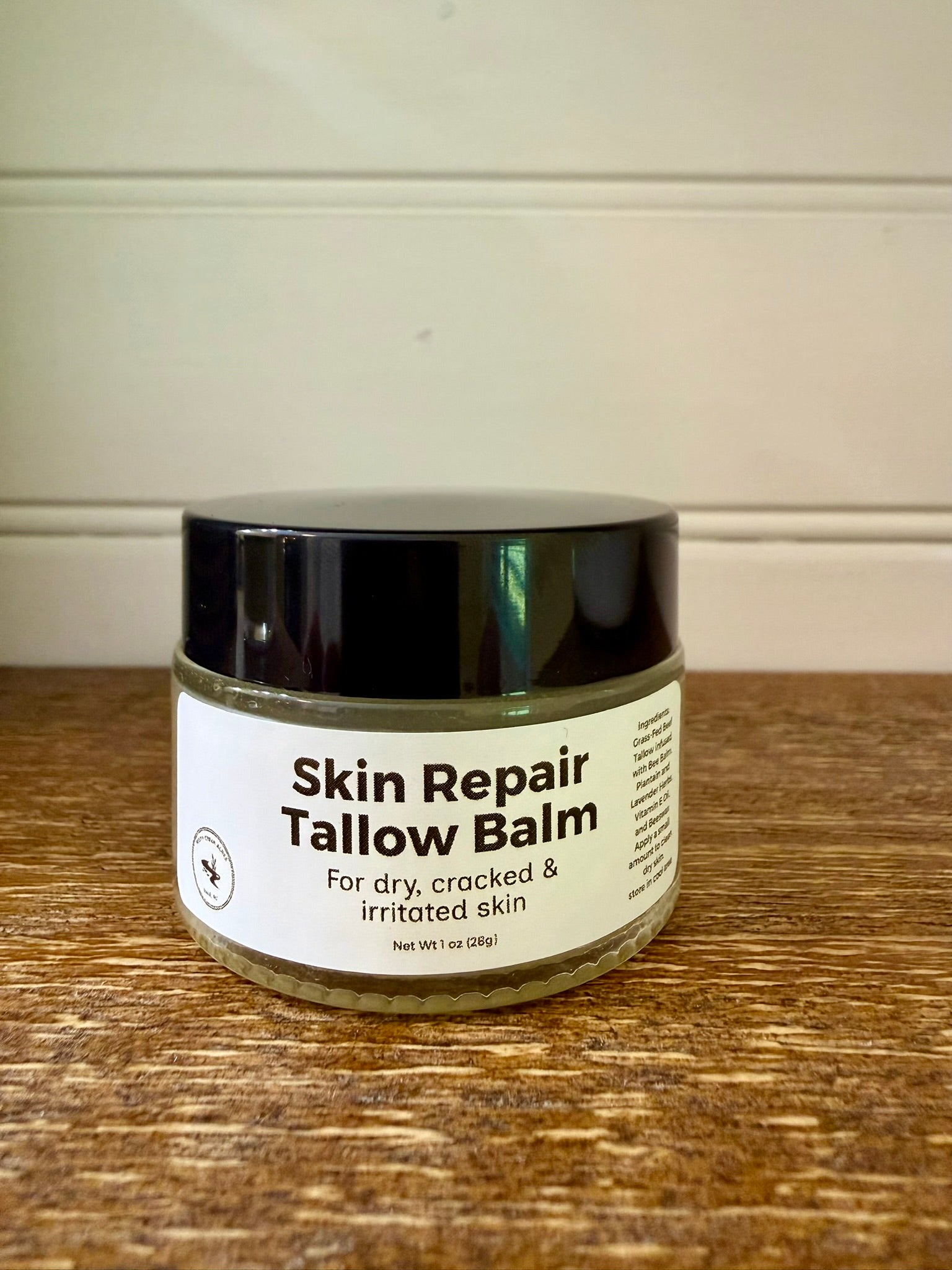 Jar of Skin Repair Tallow Balm on a wooden surface with a neutral background