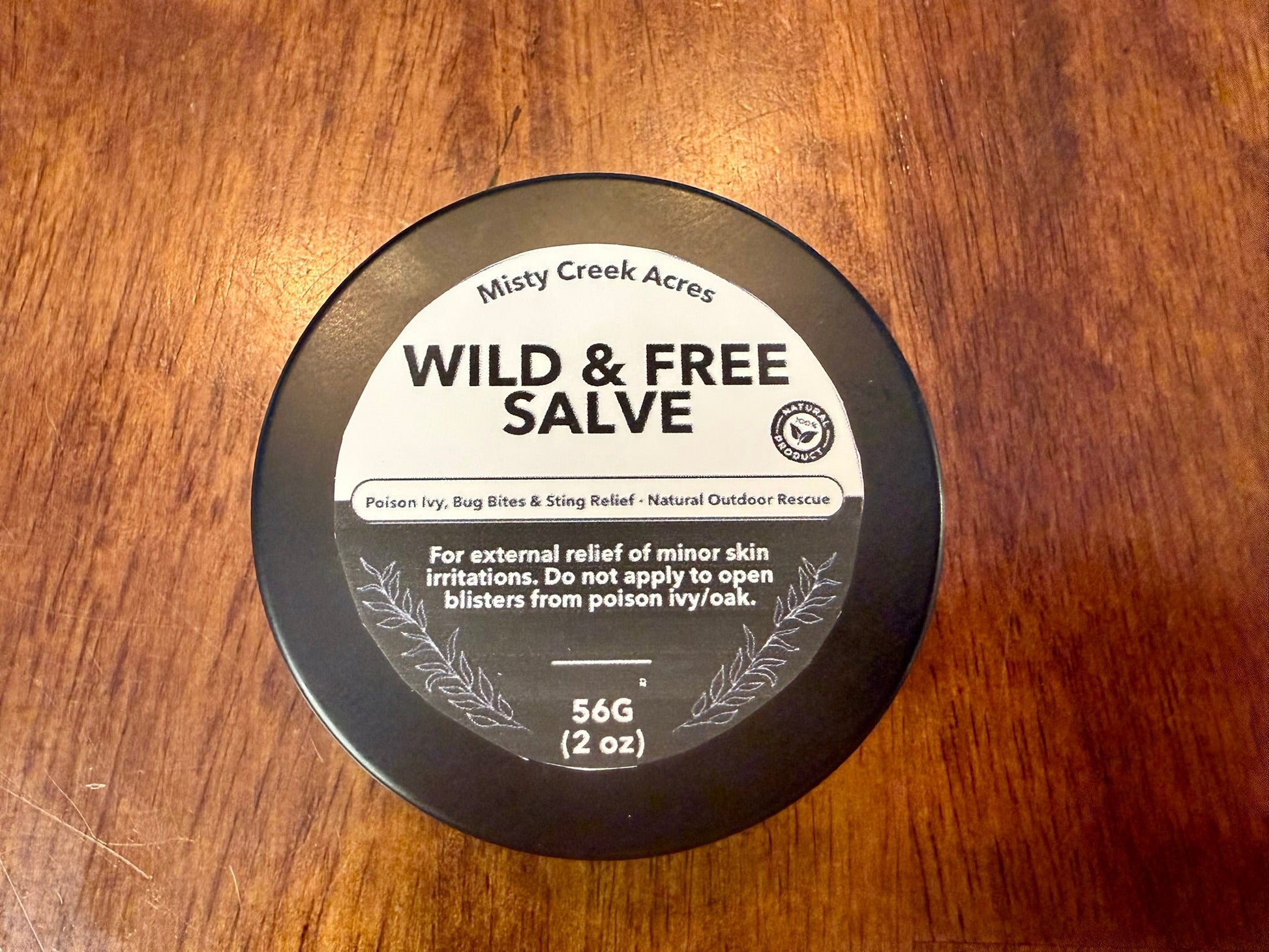 Container of Wild & Free Salve on a wooden surface