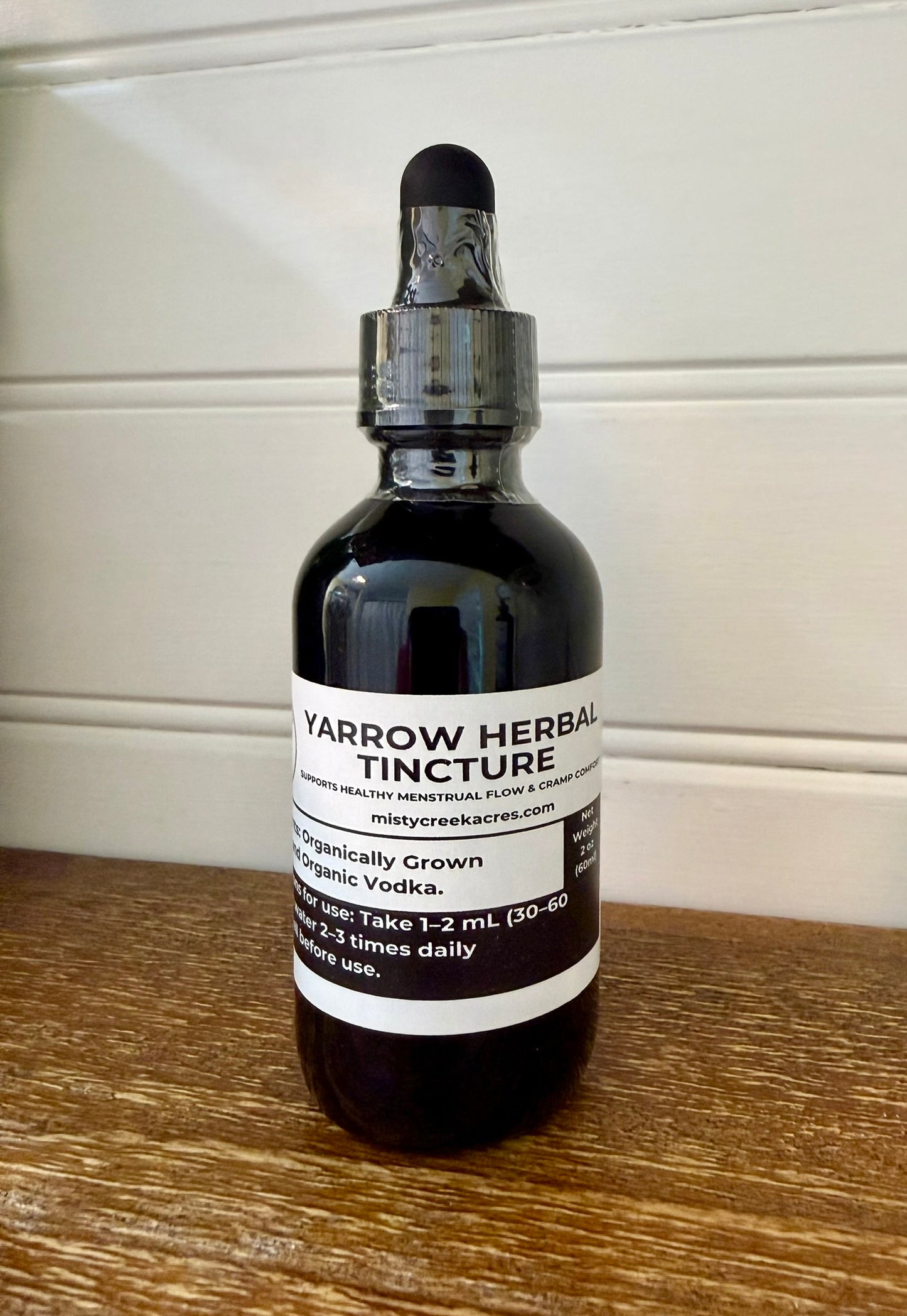 Bottle of yarrow herbal tincture on a wooden surface with a white background