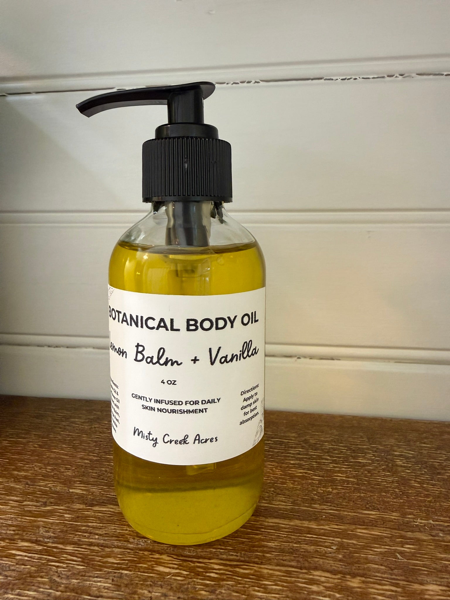Bottle of botanical body oil with a label on a wooden surface