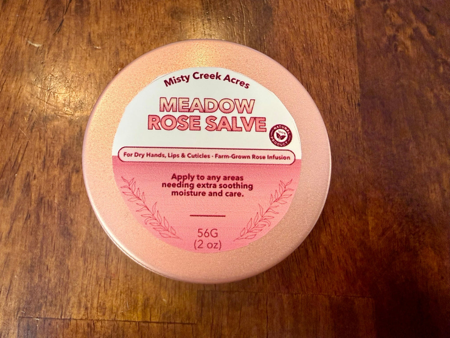 Meadow Rose Salve container on a wooden surface