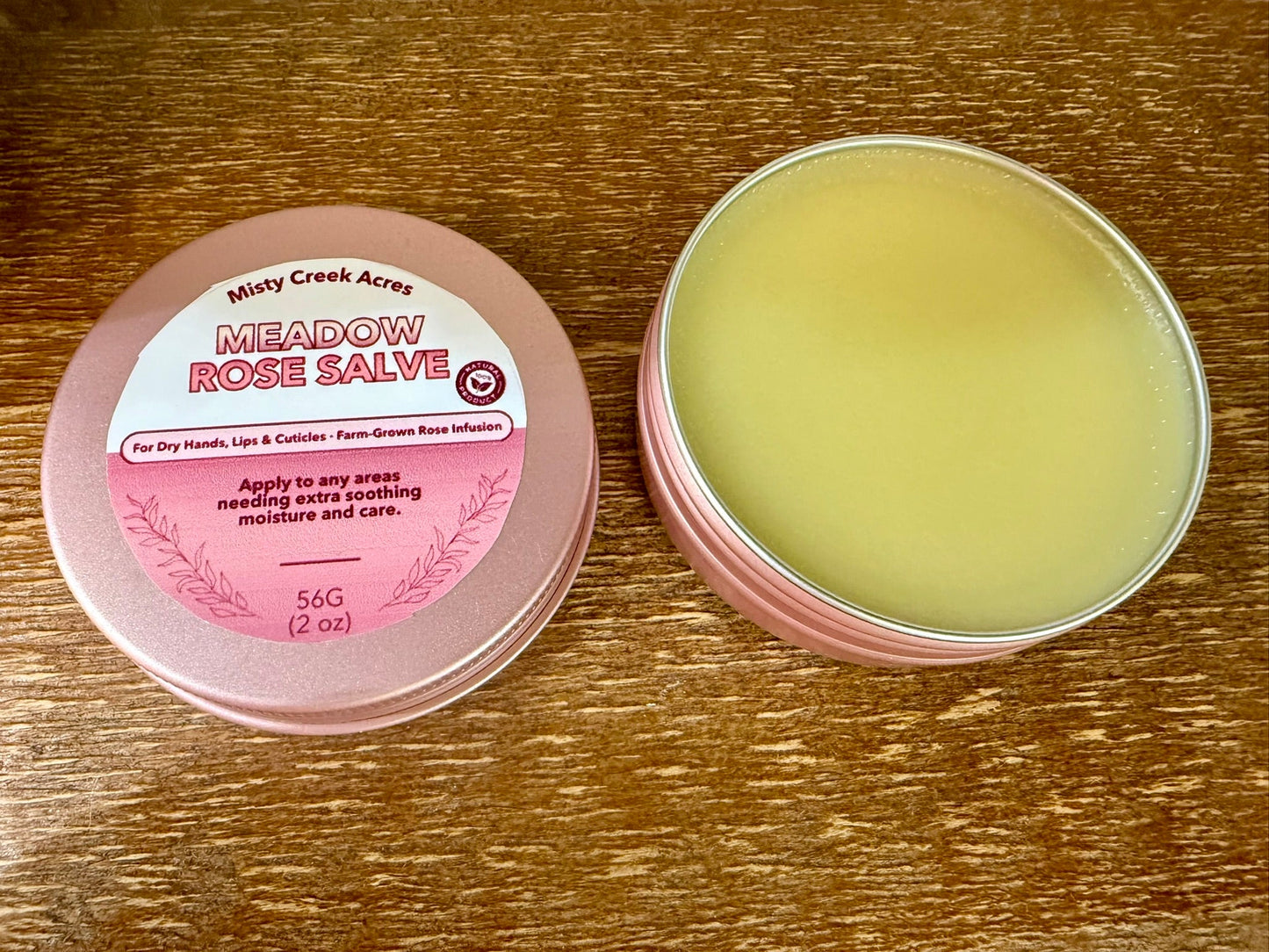 Meadow Rose Salve container with pink lid on a wooden surface