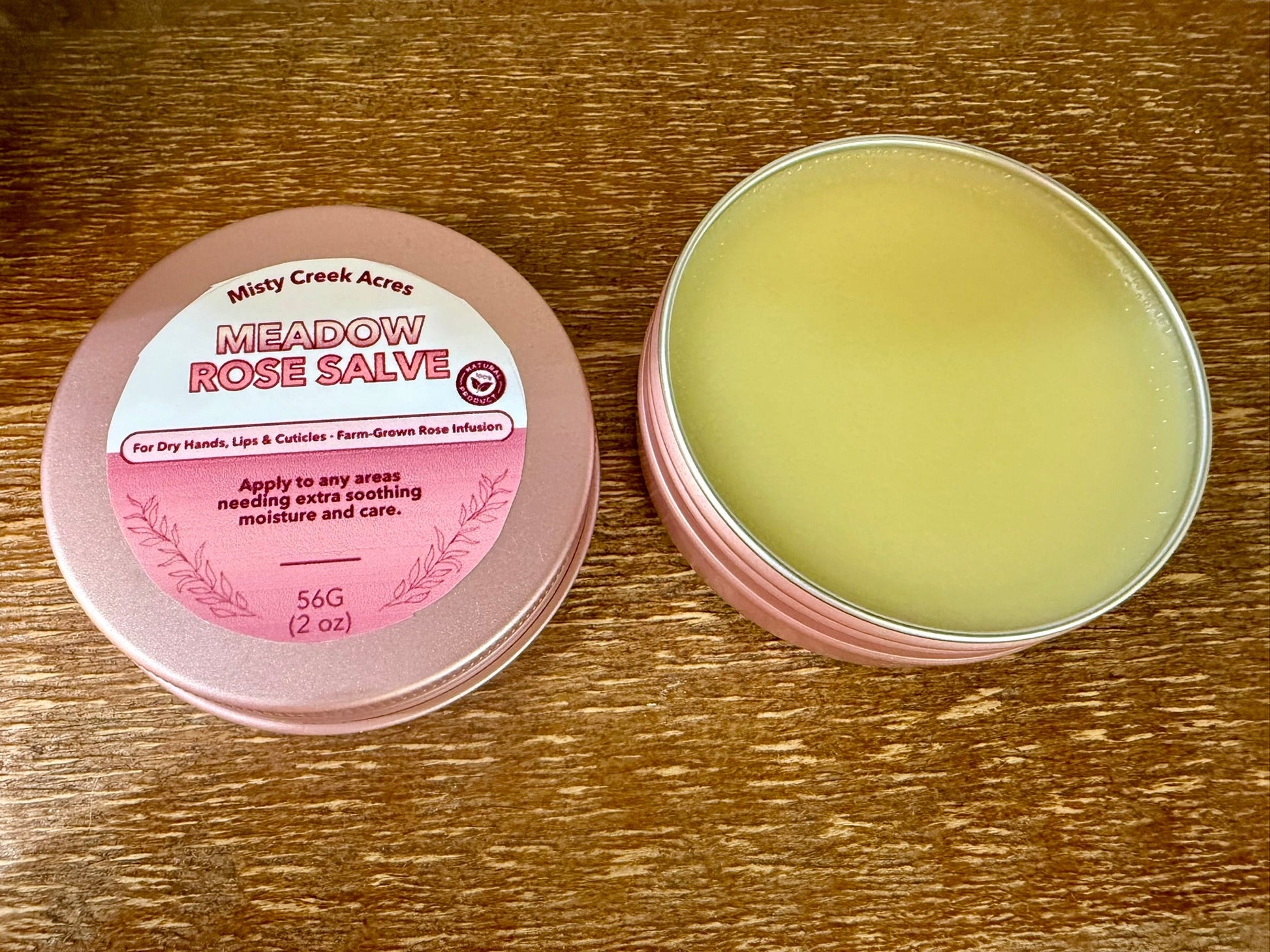 Meadow Rose Salve container with pink lid on a wooden surface