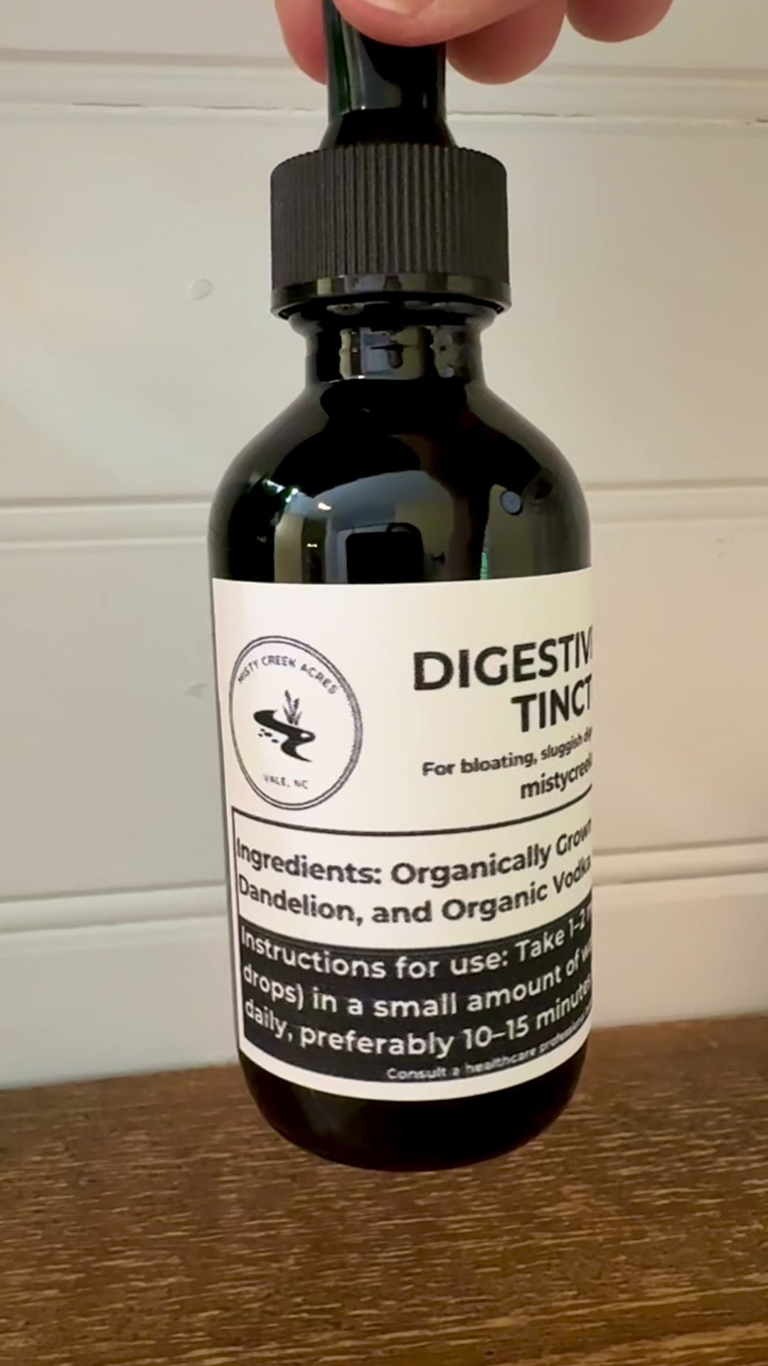 Bottle of digestive tincture on a wooden surface with a white wall background