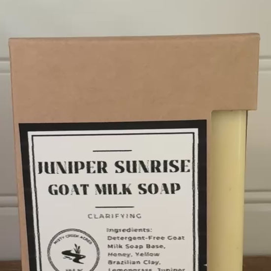 Bar of soap and its packaging with 'Hexxer Sunrise Goat Milk Soap' label on a wooden surface.