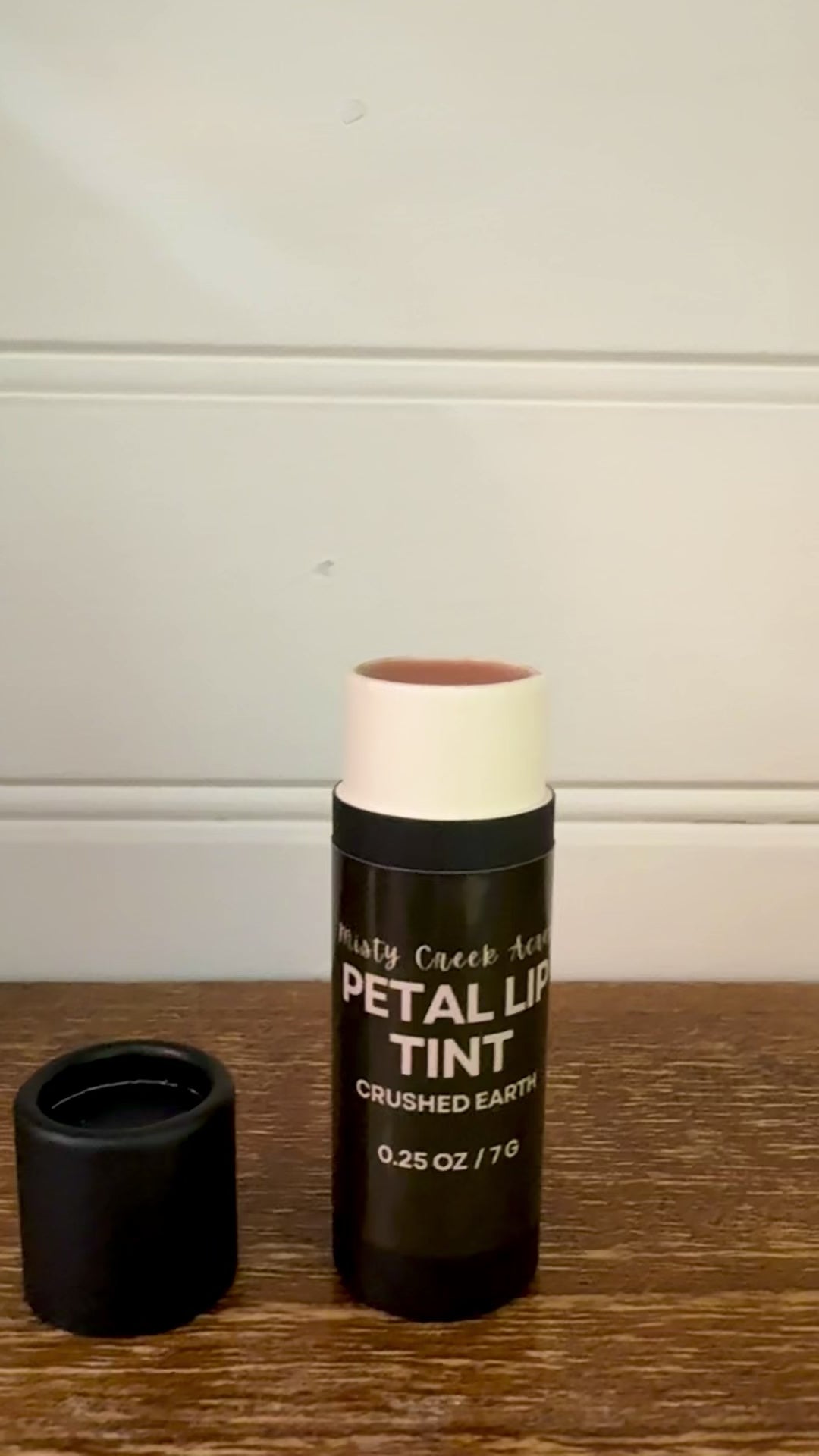 Balm with a black container on a wooden surface