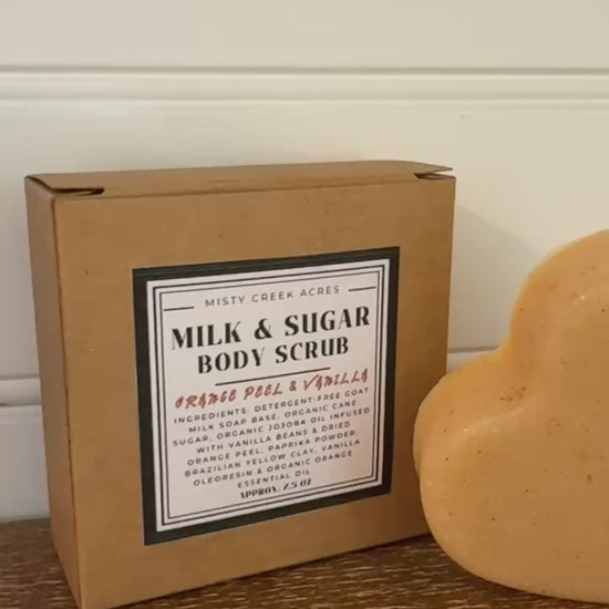 Heart-shaped body scrub with two boxes labeled 'Milk & Sugar Body Scrub' on a wooden surface.