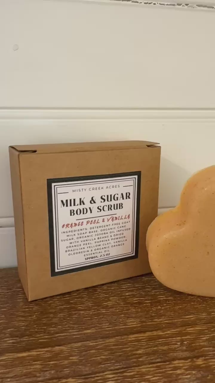 Heart-shaped body scrub with two boxes labeled 'Milk & Sugar Body Scrub' on a wooden surface.