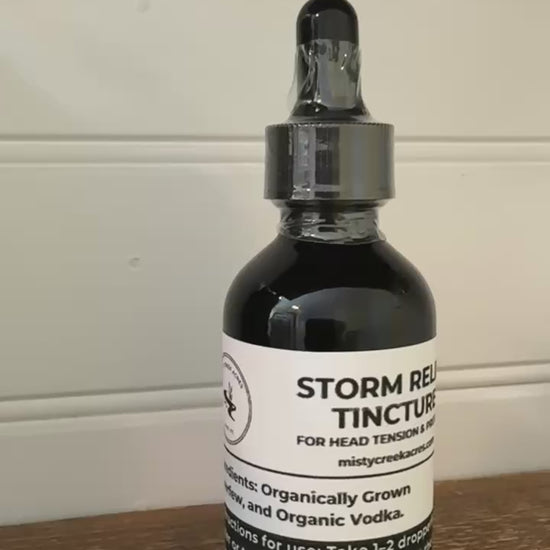 Bottle of Storm Relief Tincture on a wooden surface with a white wall background
