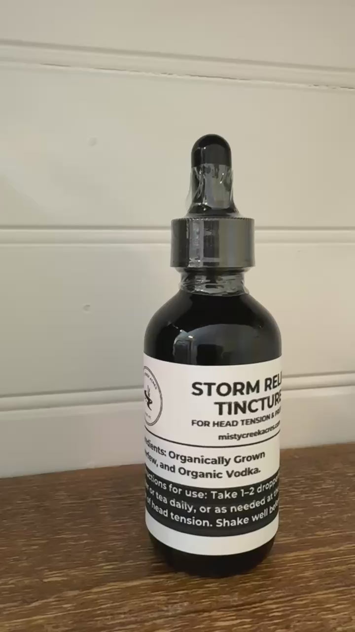 Bottle of Storm Relief Tincture on a wooden surface with a white wall background