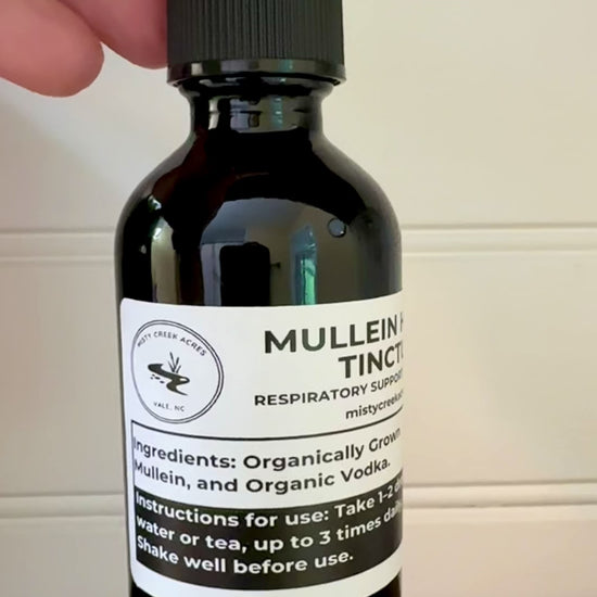 Bottle of Mullein Herb Tincture on a wooden surface with a white wall background
