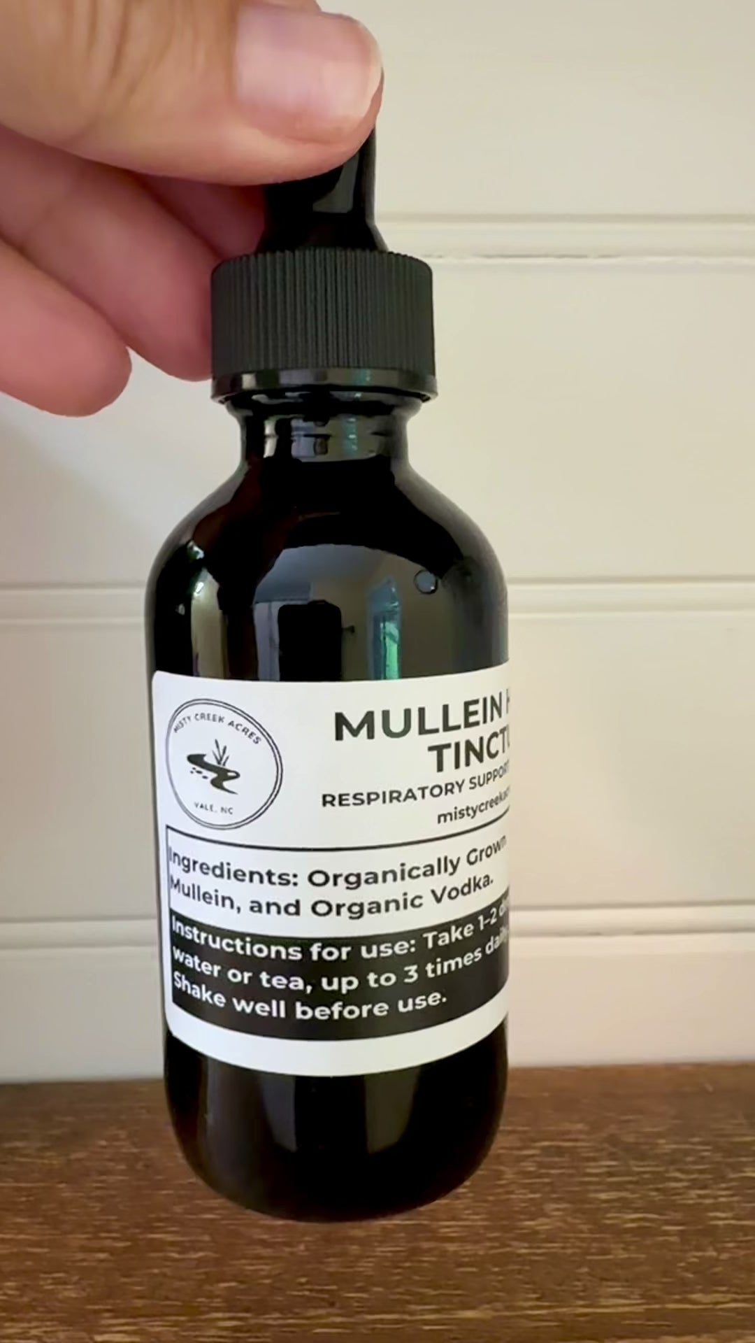 Bottle of Mullein Herb Tincture on a wooden surface with a white wall background