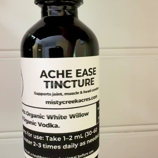 Bottle of Acme Ease Tincture on a wooden surface with a white wall background
