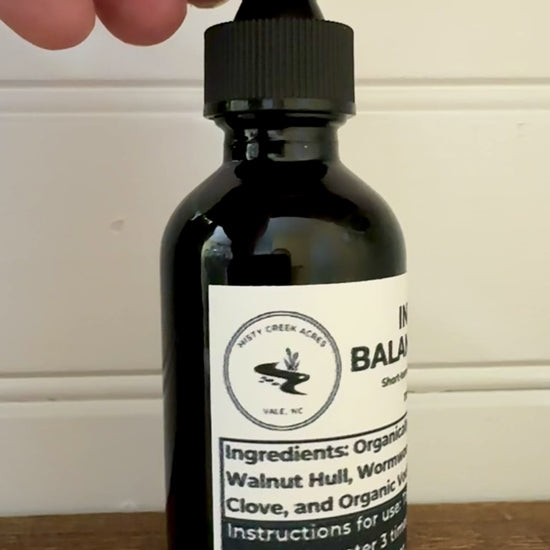Bottle of Intestinal Balance Tonic on a wooden surface with a white wall background