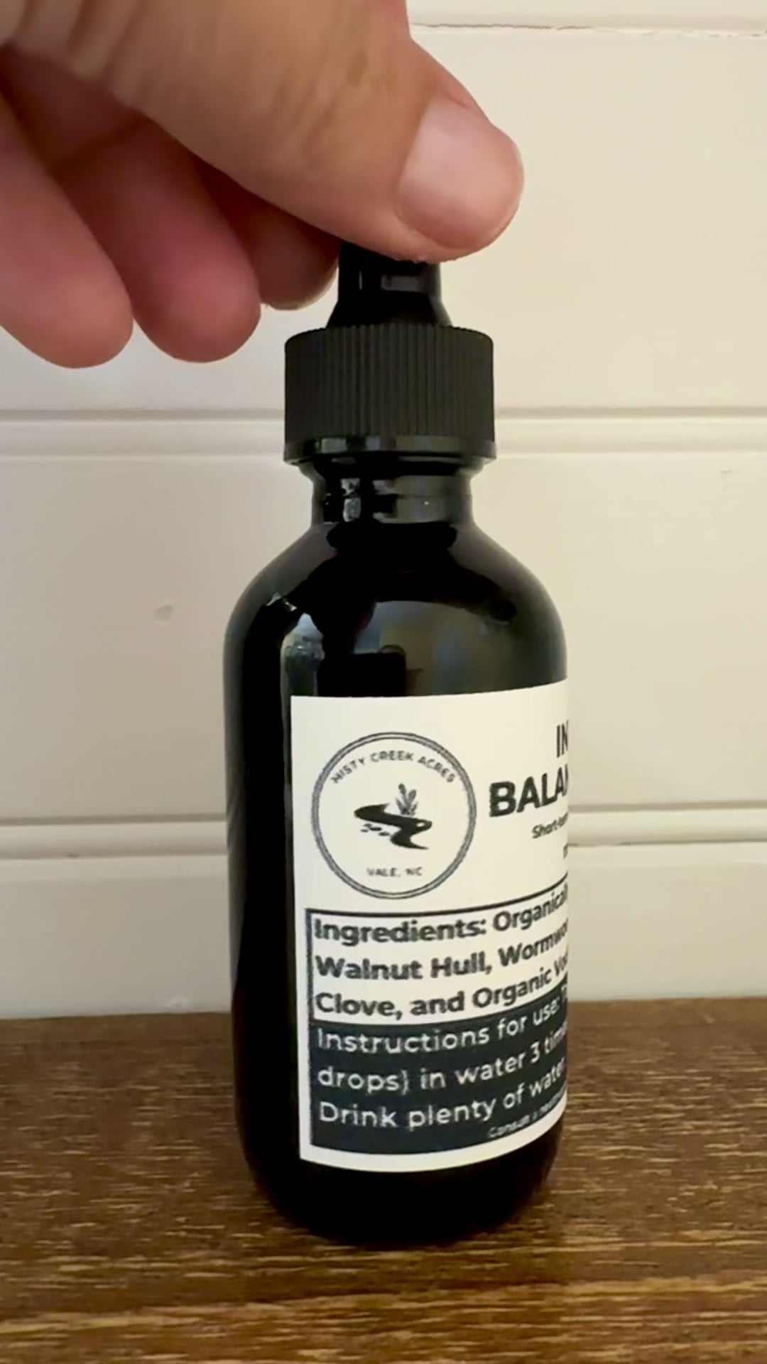 Bottle of Intestinal Balance Tonic on a wooden surface with a white wall background