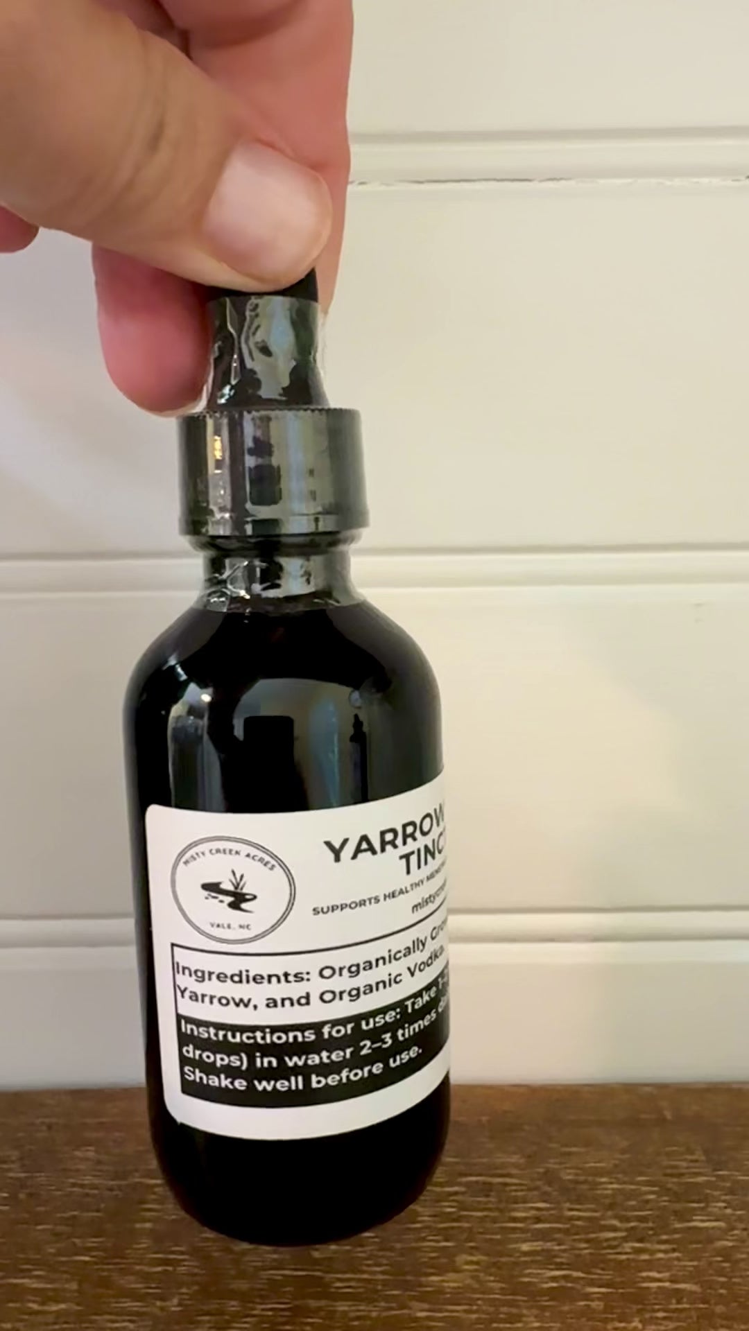 Bottle of yarrow herbal tincture on a wooden surface with a white background