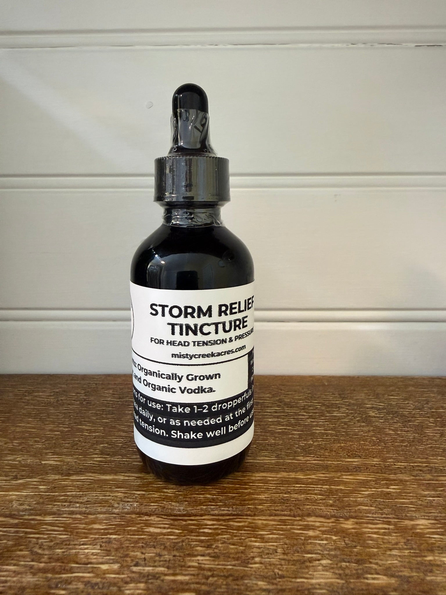 Bottle of Storm Relief Tincture on a wooden surface with a white background