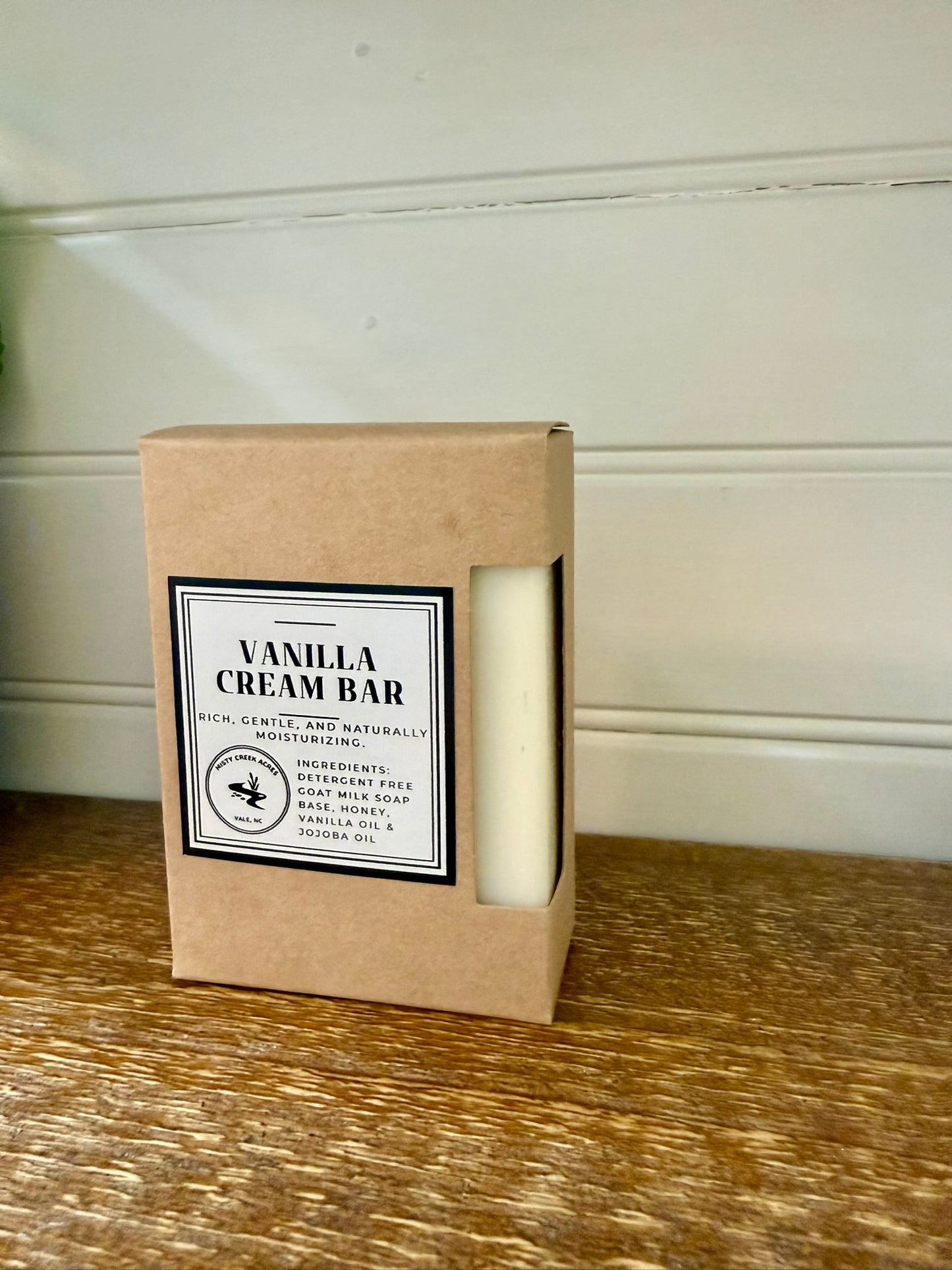 Vanilla cream bar in a cardboard box on a wooden surface with a white wall background