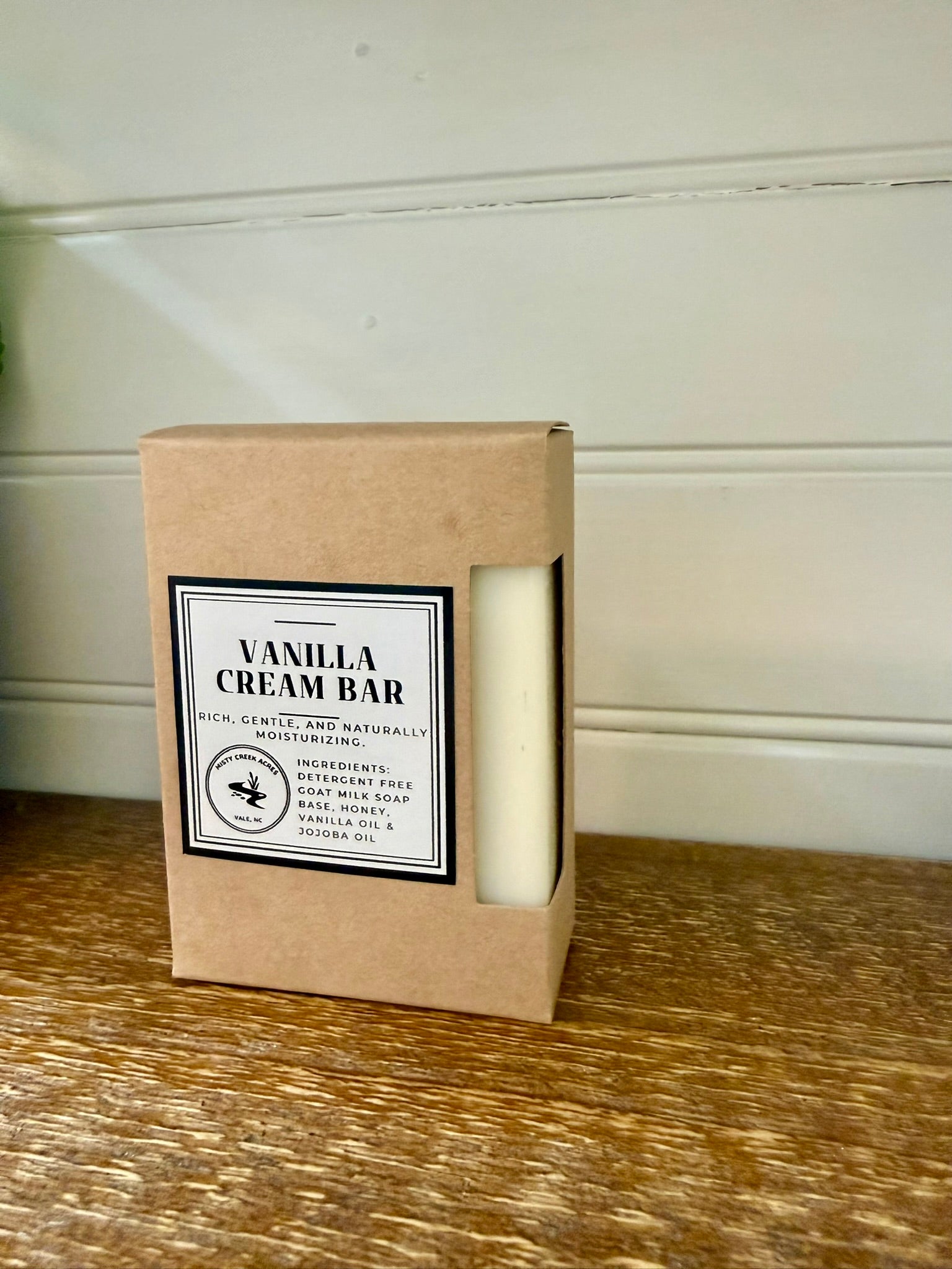 Vanilla cream bar in a cardboard box on a wooden surface with a white wall background