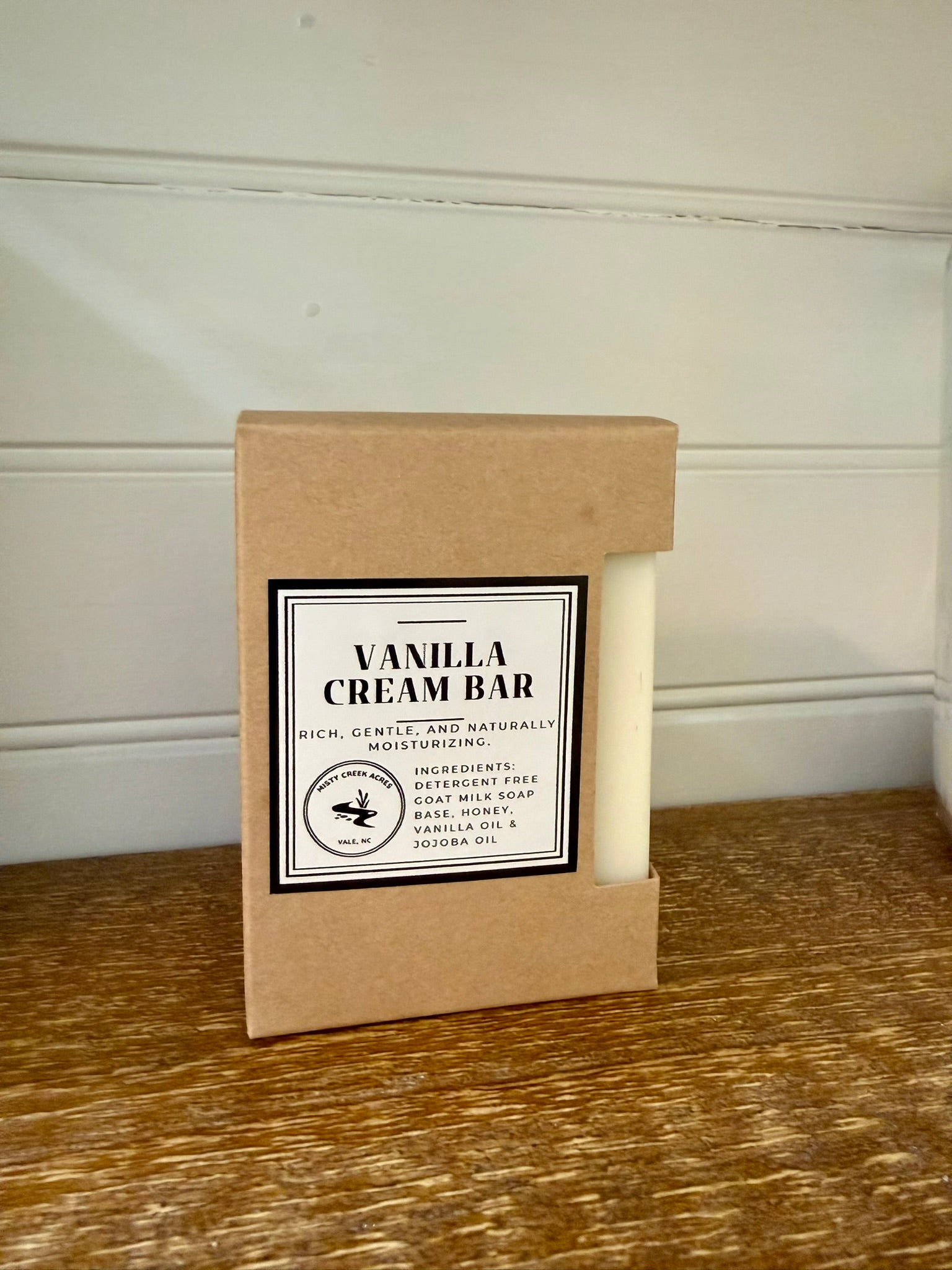 Vanilla cream bar in a cardboard box on a wooden surface with a white wall background