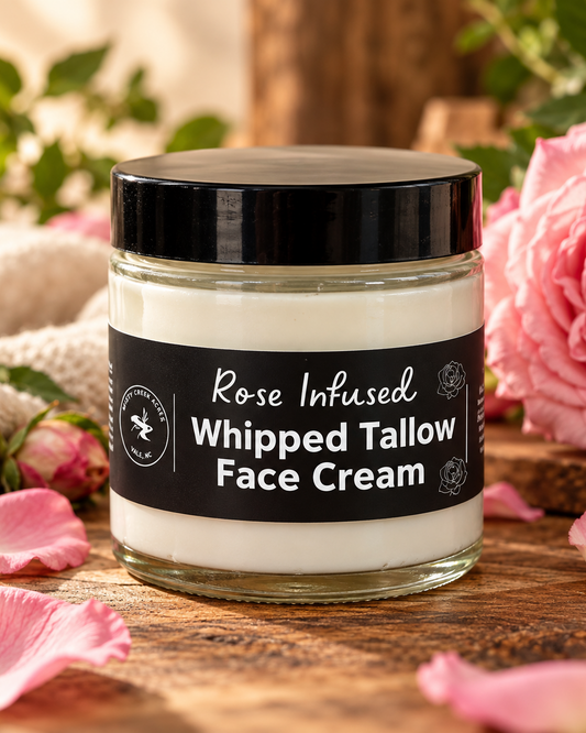 A jar of Rose Infused Whipped Tallow Face Cream with a black lid and black label, set against a light wood grain background.
